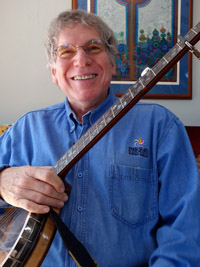 Howie's face is full of joy as he holds the neck of his banjo across his chest.